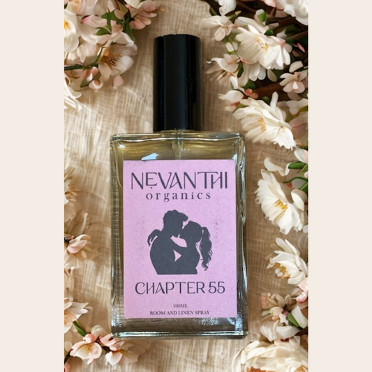Nevanthi Organics perfume bottle with a pink label on a floral background, Bottle of Chapter 55 room spray with lavender and sandalwood – inspired by fantasy romance books

