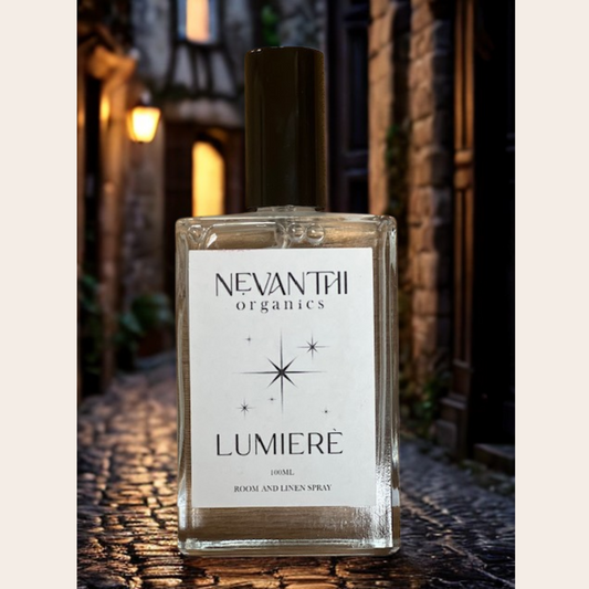Nevantii Organics Lumiere room and linen spray bottle on a textured surface with a blurred background