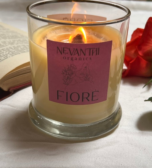 Candle with a 'Nevantii Organics Fiore' label on a white surface with a red flower.