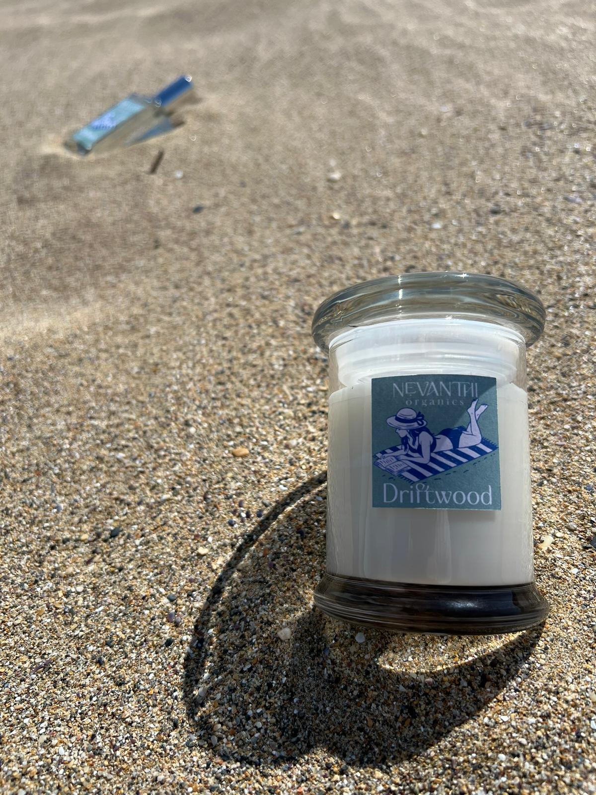 Driftwood soy candle by Nevanthi Organics — summer seasonal candle with room spray in background on Norfolk beach sand