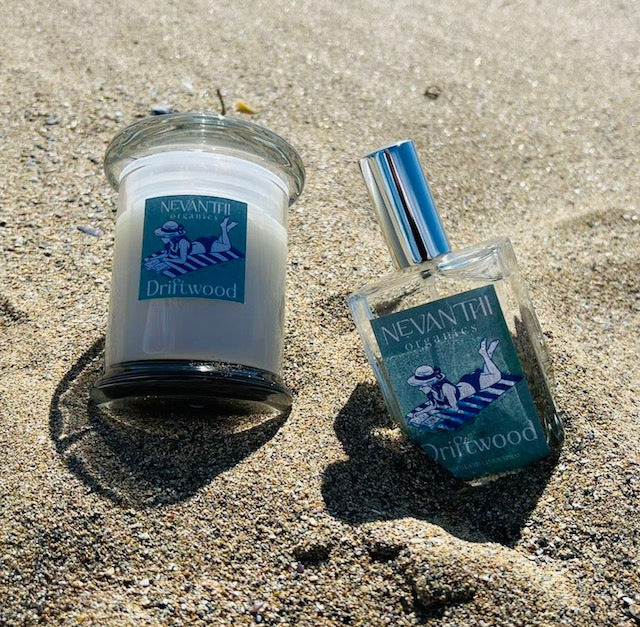 Driftwood soy candle and room spray by Nevanthi Organics — summer seasonal collection photographed on Norfolk beach with sea and blue sky