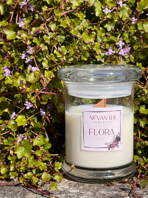 lora candle by Nevanthi Organics — handmade UK spring soy candle styled against flowering ivy wall in natural light